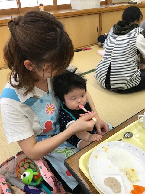 お母さんが赤ちゃんに離乳食を食べさせている様子の写真