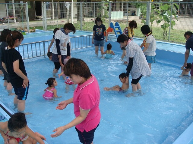 育児講座でプール遊びをする園児たちと保護者の皆さんの写真