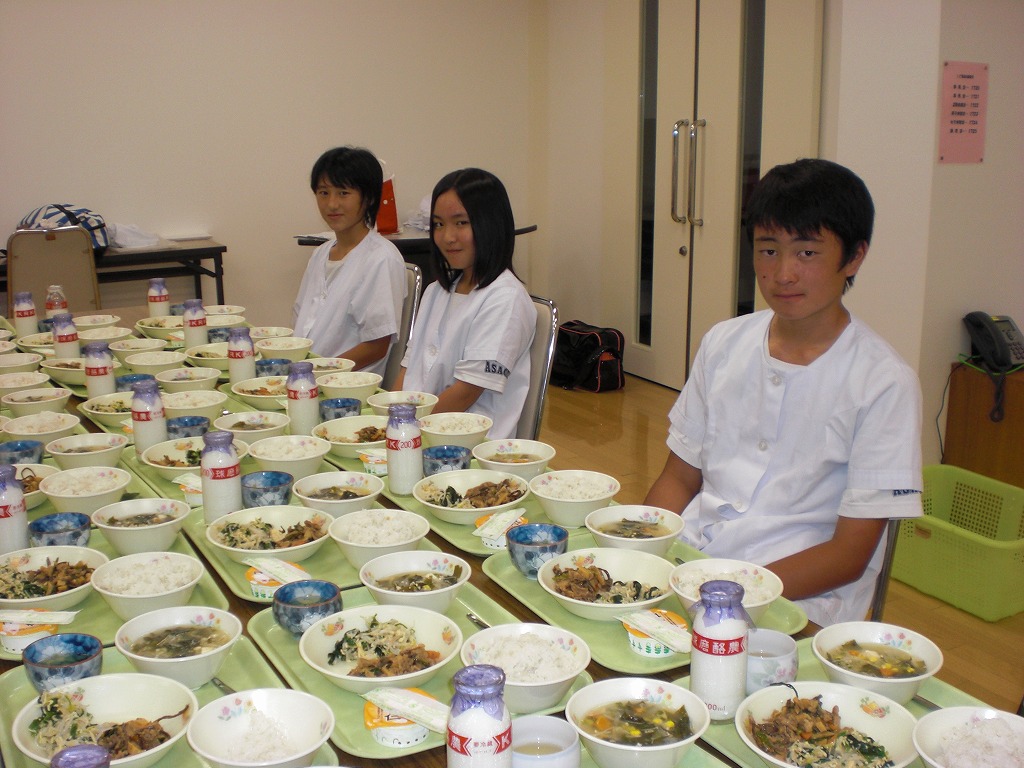 職場体験学習にきた生徒3人と机に並んだ給食の写真