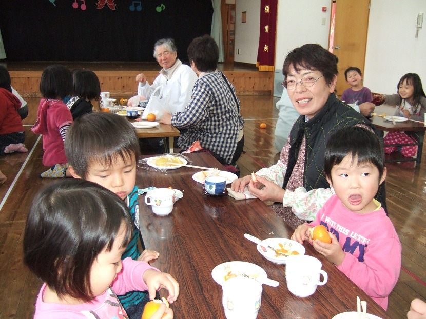 もちを食べるおばあちゃん達と園児達の写真
