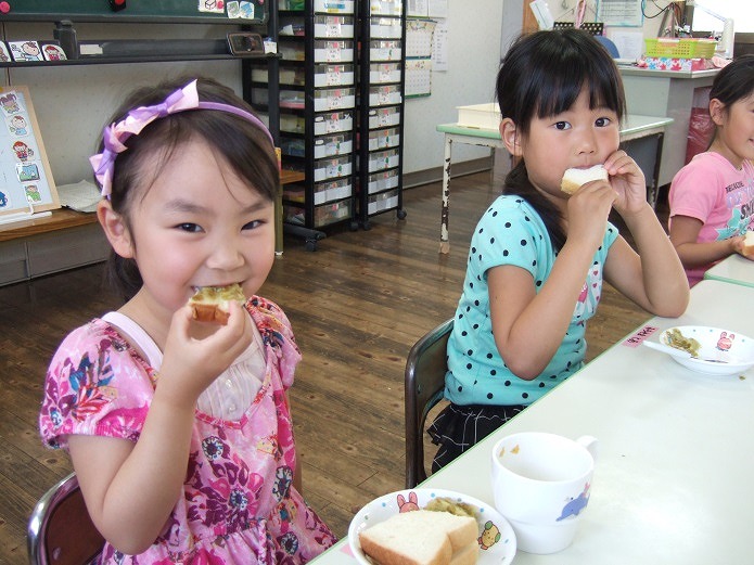 梅ジャムを塗ったパンを食べる園児たちの写真