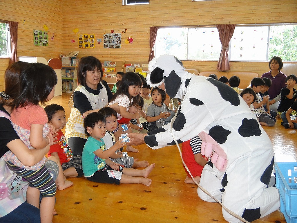 着ぐるみの牛さんから牛乳を受け取る園児の写真