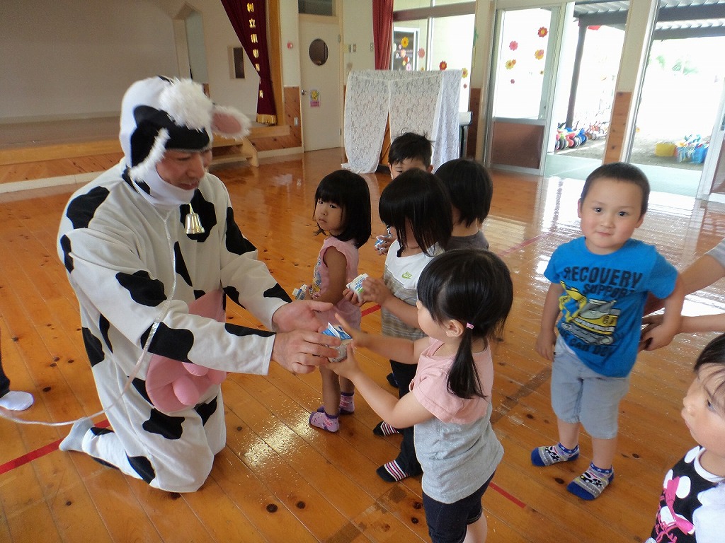 牛乳をプレゼントしてくださったホワイト酪農の方と受け取る園児たちの写真